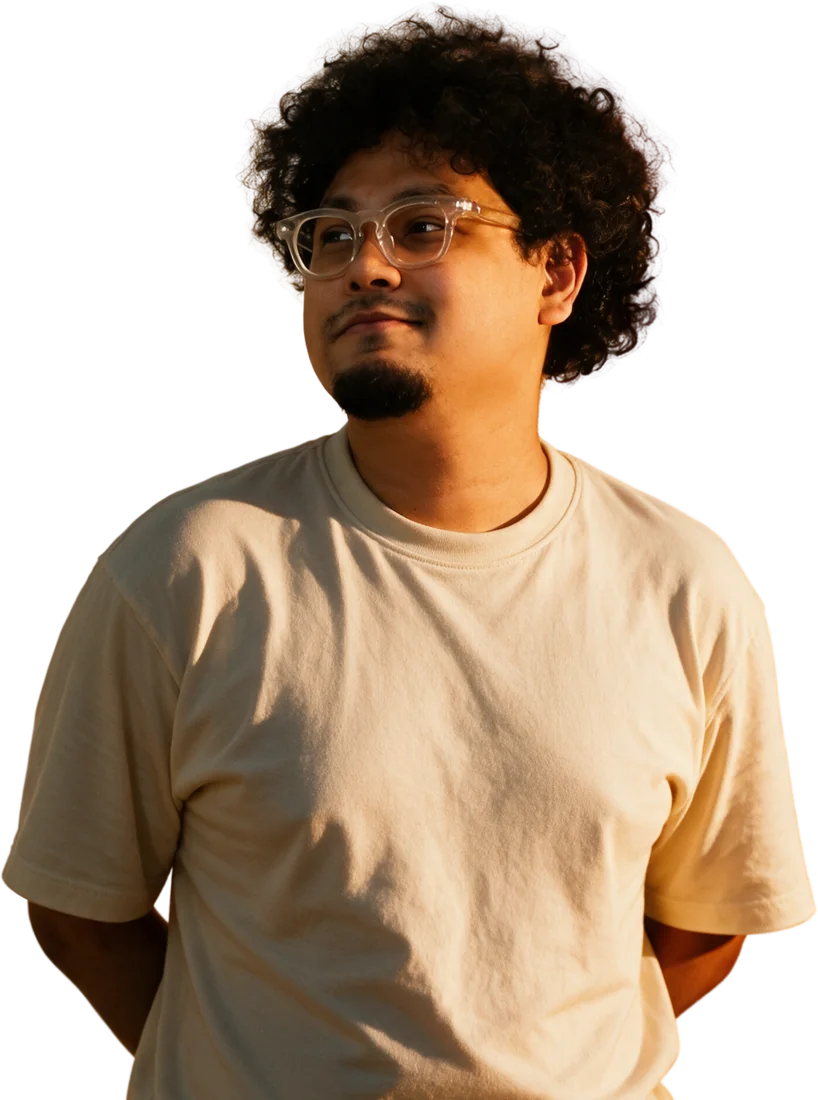 Adib Al Ibrahim in a cream t-shirt and clear glasses, smiling and looking to the side in warm sunset light